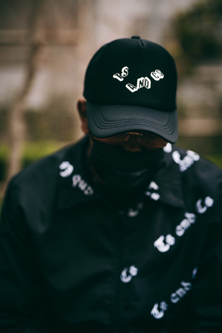 Close-up of a black Ts and Cs cap with white 3-D lettering